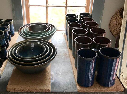 Nesting bowls and tall mugs catching the light - timeless beauty.