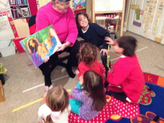 We encourage families to participate in our program. A child's grandma is reading stories to children