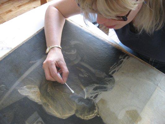 Jill Pratzon removing dirt and discolored varnish to reveal the painting's original colors.