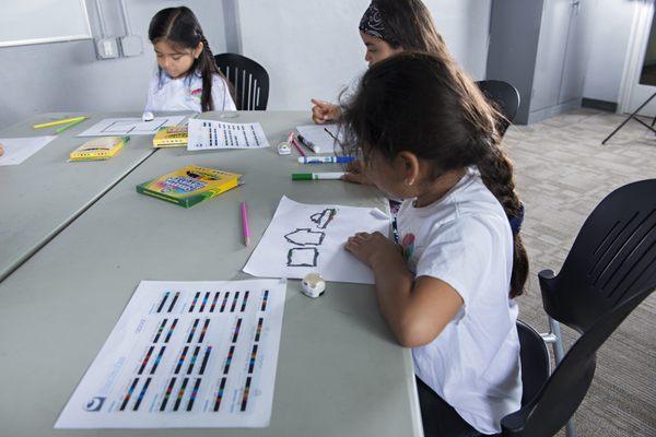 These girls are experimenting with line coding. They are using the color codes to make the Ozobot do special moves.