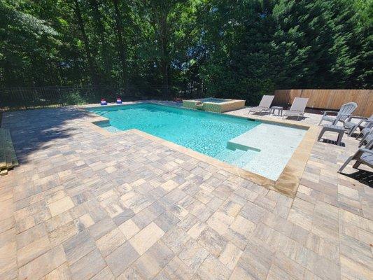 This is a 17.5'x37' sport pool with a sun shelf on one end. Steps on both ends. Raised square spa. Travertine, PebbleSheen and Tremron used.