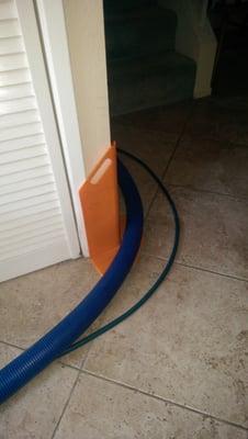 Orange shield protecting wall corner from carpet cleaning hose