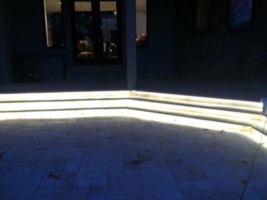 While LED outdoor tape lighting installed under travertine steps