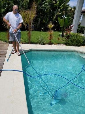 one of our technicians using a hammerhead to vacuum a customer's pool.