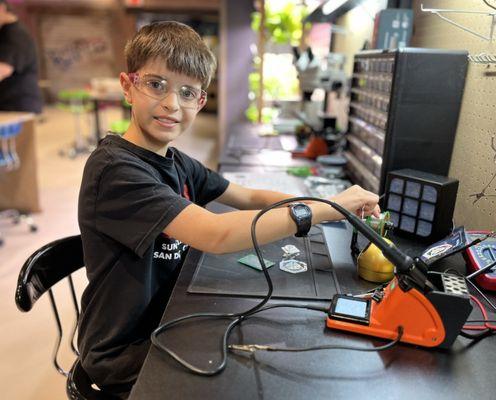 Member soldering an electronics badge.