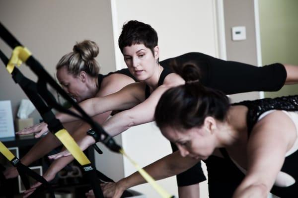 Traci checking client's form during TRX class