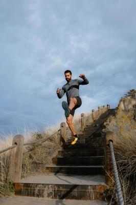 A man rushes down a flight of stairs, his feet clad in a pair of innovative and stylish shoes.