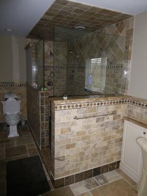 Marble and limestone bathroom.  Custom multi head walk in shower with frameless glass walls.