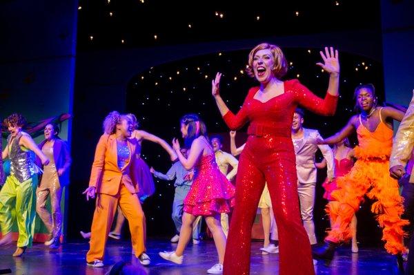 Emma Luxemburg and company, dancing & singing in colorful costumes in the spring 2023 production of The Prom, directed by Emma Pittman