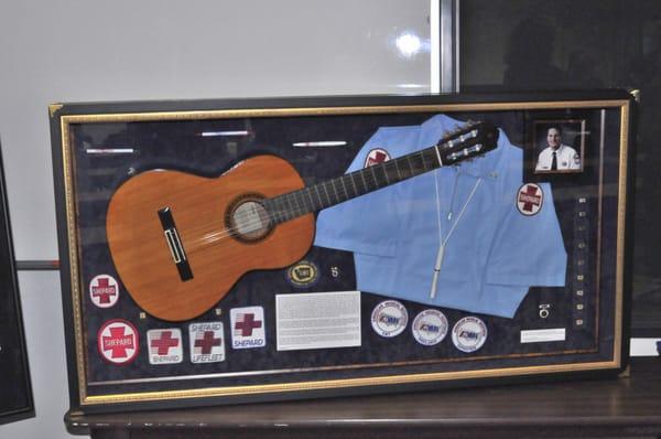 A shadow box tribute featuring an acoustic guitar and various awards.