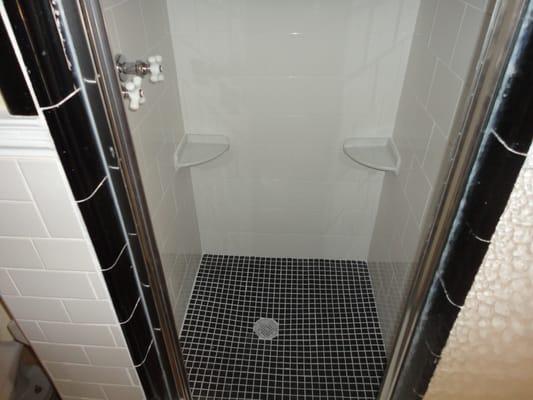 New shower installed. He used the original black tile because it had a nice curve to it. The chips are going to get covered up.