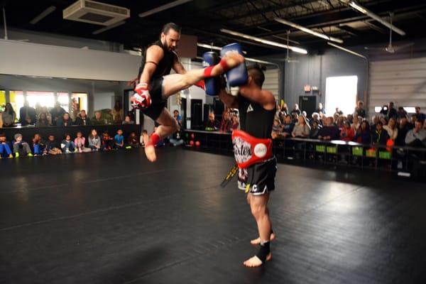 Master White kicks as Master RJ Lee holds pads